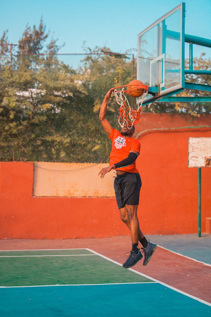 Man performing a basketball dunk on an outdoor court. Captivating sports action shot.